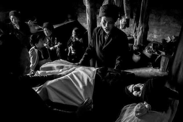 Female members of the Yi tribe mourn the death of an elderly man who has been prepared for his burial. Zhaojue, Sichuan &ndash; China. Image &copy; Michael Coyne.