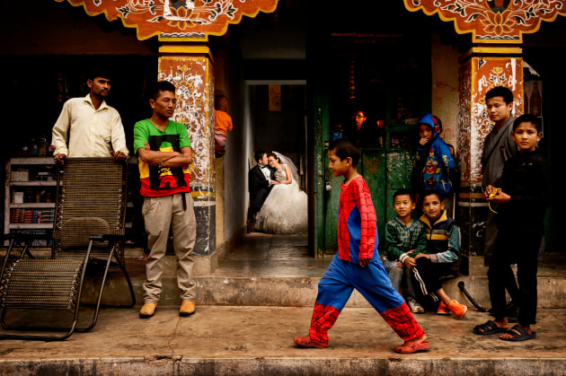 © Chrisman Studios. Taiwan couple Christine and Chiaming cuddle in an alleyway while the townspeople of Paro, Bhutan, walk past.