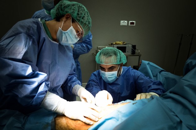 &copy; Darrian Traynor, from the series, 'More than skin deep'. GAZA. 4th March 2020. Surgeons inspect the wound after removing an external fixator. Al-Awda hospital patients suffering from osteomyelitis are kept in isolation rooms to treat infection. No new bone plantations can be performed while the infection is present.