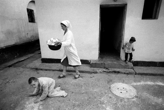 © William Snyder. Mimi Rizescu carries empty lunch containers back to the kitchen after feeding nearly 20 children of various ages in the Home for Irrecoverables in Vulturesti, Romania. May, 1990. Mimi does her best to feed, clothe and comfort the children in her charge for 10 hours a day, 6 days a week. This image is one of 12 images that won the 1991 Pulitzer Prize in Feature Photography.